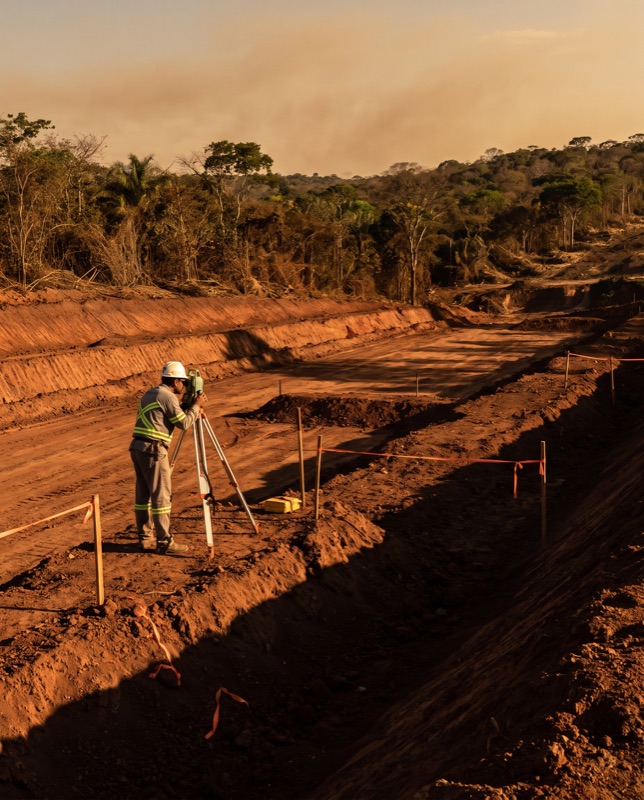 Topógrafo operando estação total em terreno de terraplenagem